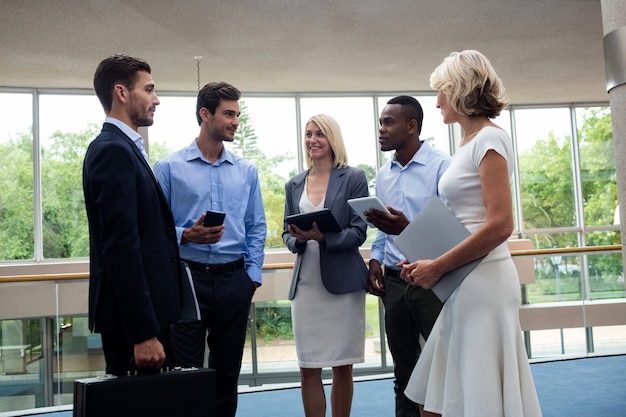 A diverse group of professionals engaging in a networking event after completing a job training program. They are exchanging business cards and discussing career opportunities, signifying successful program outcomes.