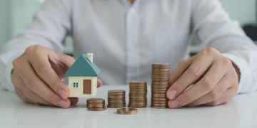 Hands holding a miniature house and stacked coins, symbolizing 401k retirement growth and employer match benefits.