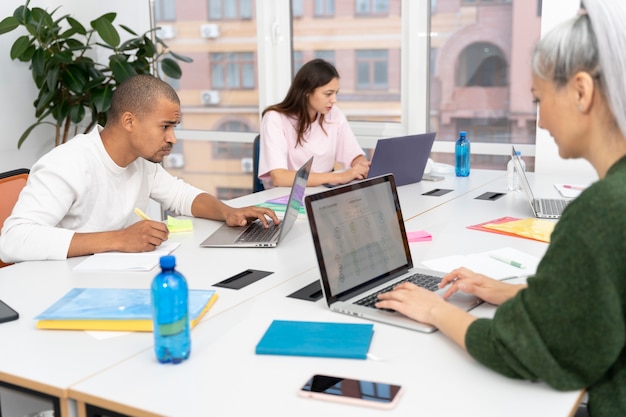 A diverse group of students collaborating on a project in a modern classroom, surrounded by laptops and presentation screens, indicating a Master's level program focusing on practical skills.